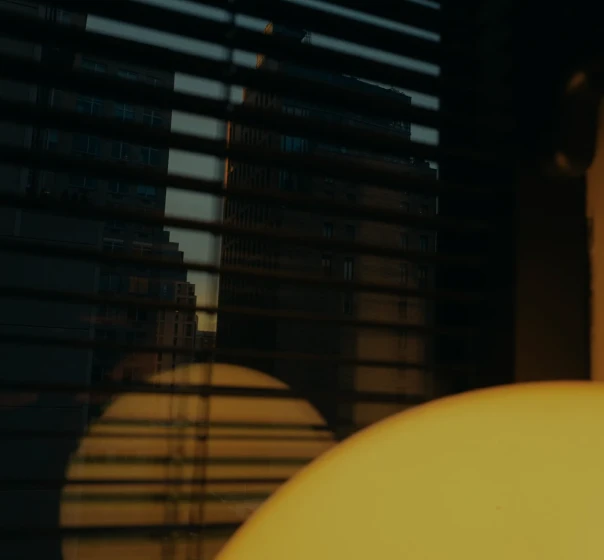 Low sun through window blinds onto a yellow wall